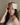 Woman wearing a champagne deep restoration sleep mask on her forehead while sitting in bed. 