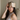 Woman wearing a champagne deep restoration sleep mask on her forehead while sitting in bed. 