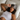 Woman with curly hair with a dark gray deep restoration sleep mask on her forehead while she is laying on a white silk pillowcase.