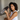 Woman holding a Dark Gray Deep Restoration Silk sleep mask in her hands showing the soft, pillowy feel of it while sitting in bed.