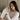 Woman holding a Light Gray Deep Restoration Silk sleep mask in her hands showing the soft, pillowy feel of it while sitting in bed.